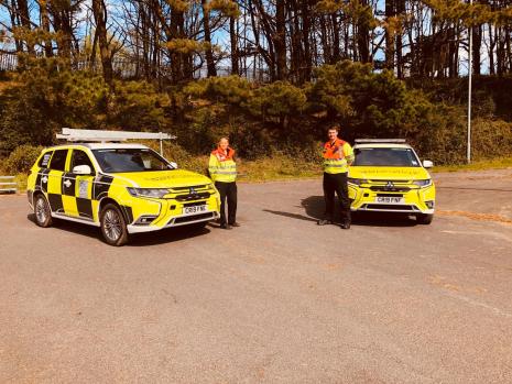 2 traffic offcers standing next to traffic officer vehicles